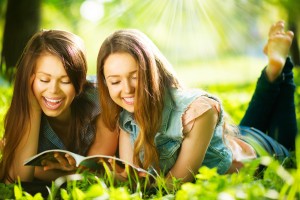 Happy teenage girls reading a magazine outdoors